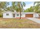 White house with brown garage door, landscaping, and a palm tree at 2255 S Lagoon Cir, Clearwater, FL 33765