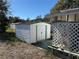 White storage shed with double doors, adjacent to a lattice-fenced patio area at 37402 Hammond Dr, Zephyrhills, FL 33541