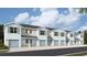 Row of modern townhomes featuring light gray siding, blue shutters, and single-car garages, under a bright sky at 4648 Pleasant Ave, Palm Harbor, FL 34683