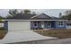 Newly constructed home with a blue exterior, white garage door, and a well-maintained lawn at 5211 Peach Ave, Seffner, FL 33584