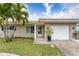 Tan house with a white garage door and palm trees in front at 809 Mandalay Ave, Clearwater Beach, FL 33767