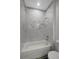 Clean bathroom with marble-look tile and a white bathtub at 11926 Riverhills Dr, Tampa, FL 33617