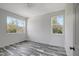 Well-lit bedroom featuring wood-look floors and two large windows at 11926 Riverhills Dr, Tampa, FL 33617