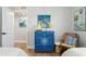 Bedroom with blue dresser, rocking chair, and coastal art at 3200 Gulf Blvd # 204, St Pete Beach, FL 33706