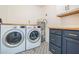 Laundry room with washer, dryer, and dark blue cabinets at 3709 W Oklahoma Ave, Tampa, FL 33611