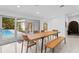 Bright dining room with wooden table and bench, view of the pool at 5027 Sunrise S Dr, St Petersburg, FL 33705