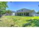 Large backyard with grassy area, wooden fence, and home with covered patio at 5103 Ashcrest Ct, Tampa, FL 33647