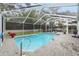 Inviting pool area with screened enclosure, patio furniture, and lush landscaping at 8535 Delaware Dr, Weeki Wachee, FL 34607