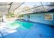 Screened pool with a slide, surrounded by a partially shaded deck at 8615 Greenfield Ln, Zephyrhills, FL 33541