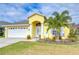 Yellow house with white garage door, palm tree, and landscaped lawn at 11511 Lounds Ct, New Port Richey, FL 34654