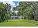 Expansive backyard featuring lush green lawn, mature trees, and a charming white home with screened porch at 11624 Monette Rd, Riverview, FL 33569