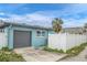 Detached garage with dark gray door and white fence at 117 73Rd Ave, St Pete Beach, FL 33706