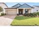 One-story home with gray siding, a tan garage door, and a landscaped lawn at 12292 Lyon Pine Ln, Odessa, FL 33556