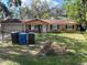 Brick house with attached garage, mature trees, and a fenced yard at 14810 N 30Th St, Lutz, FL 33559