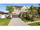 Two story house with tan exterior, brown garage door, and palm trees at 19231 Pepper Grass Dr, Tampa, FL 33647