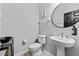 Modern bathroom with a pedestal sink, oval mirror and toilet at 29913 Southwell Ln, Wesley Chapel, FL 33543