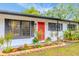 Updated ranch home with red door, landscaping, and modern exterior at 4702 W Bay Ave, Tampa, FL 33616