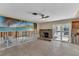 Living room with tile flooring, stone fireplace, ceiling fan, sliding glass doors, and a mural of a beach scene at 4801 Venetian Ne Pl, St Petersburg, FL 33703