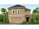 Two-story house with tan exterior, dark gray roof, and a two-car garage at 5322 Oxford Gray Rd, Wesley Chapel, FL 33545