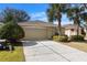 Front view of a tan house with a two-car garage at 10833 Collar Dr, San Antonio, FL 33576