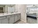 Double vanity bathroom with gray cabinets and a shower at 12143 Kingsley Trl, Parrish, FL 34219