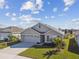 Tan one-story house with gray roof, three-car garage, and landscaped yard at 12143 Kingsley Trl, Parrish, FL 34219