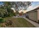 Picturesque backyard features a lush lawn, tropical landscaping, outdoor bar area, and screened-in pool at 1301 Eniswood Pkwy, Palm Harbor, FL 34683