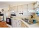 Bright kitchen features white cabinets, an electric range and a corner sink at 35138 Dale Ave, Zephyrhills, FL 33541