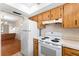 Bright kitchen features wood cabinets, white appliances, and a view into the dining area at 4746 Azalea Dr # 203C, New Port Richey, FL 34652
