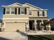 Two-story house with beige exterior, stone accents, and a three-car garage at 10913 Kidron Valley Ln, Tampa, FL 33625