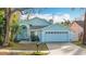 Light blue house with a two-car garage and well-maintained lawn at 14721 Condor Pass, Clearwater, FL 33760