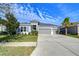 Two-story home with gray siding, three-car garage, and landscaped front yard at 17721 Bright Wheat Dr, Lithia, FL 33547