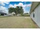 Large backyard with spacious grassy area, mature tree, and a view of a fenced-in pool at 2369 N Biscayne Dr, North Port, FL 34291