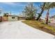 Light green house with a concrete driveway and landscaped lawn at 14081 W Parsley Dr, Madeira Beach, FL 33708