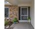 Front entry with stonework, screen door, and potted plants at 1559 Glengarry Dr, Palm Harbor, FL 34684