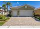 Tan house with a two-car garage and well-manicured landscaping at 16122 Cedar Key Dr, Wimauma, FL 33598