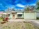 Light green house with a one car garage and nicely landscaped lawn at 1825 San Mateo Dr, Dunedin, FL 34698