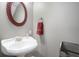 Small bathroom with pedestal sink, red framed mirror, and gray walls at 8575 Carey Rd, Lithia, FL 33547