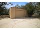 Tan metal garage with roll-up door, situated in a wooded area at 8575 Carey Rd, Lithia, FL 33547