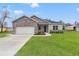 House exterior showcasing stone accents, a two-car garage, and a lush lawn at 15171 Pomp Parkway, Weeki Wachee, FL 34614