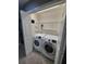 Bright laundry area with white front load washer and dryer in a closet with shelves at 7041 Spotted Deer Pl, Riverview, FL 33569