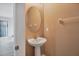 Neutral powder room featuring a pedestal sink, oval mirror and warm tan color walls at 7041 Spotted Deer Pl, Riverview, FL 33569