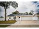 Updated single story home with a white exterior, landscaped lawn, and attached garage at 7097 Aberfeldy N Ave, St Petersburg, FL 33709