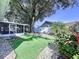 View of backyard area with rock garden, grass, patio area and mature plantings, and a screened enclosure at 7923 Leighton Cir, New Port Richey, FL 34654