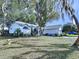 Well-maintained white home showing the facade, landscaping, and partial view of the lawn and mature trees at 7923 Leighton Cir, New Port Richey, FL 34654