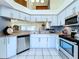 Well-lit kitchen featuring stainless appliances, white cabinets, and tiled floors at 7923 Leighton Cir, New Port Richey, FL 34654