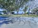 Exterior view of the house showing the screened lanai, fence, and surrounding mature trees and landscaping at 7923 Leighton Cir, New Port Richey, FL 34654