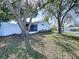 Exterior view of the house showing the screened lanai, fence, and surrounding mature trees and landscaping at 7923 Leighton Cir, New Port Richey, FL 34654