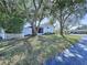 Exterior view of the house showing the screened lanai, fence, and surrounding mature trees and landscaping at 7923 Leighton Cir, New Port Richey, FL 34654