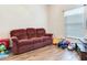 Cozy living room with a maroon couch and wood-look tile floors at 9516 Cypress Harbor Dr, Gibsonton, FL 33534